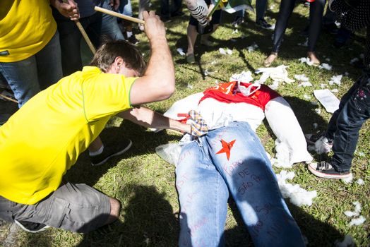 BRAZIL, Curitiba: A man hits a stuffed puppet  in front of the Federal Court in Curitiba, Brazil on March 26, 2016.Traditionally on the Saturday before Easter, Catholics beat effigies of Judas the apostle. This year protesters in favor of impeachment of the President of Brazil, used the tradition as a political demonstration.