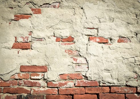 Old red brick wall with fallen plaster