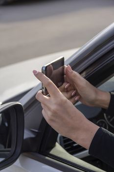 a girl takes pictures on a cell phone from the car window