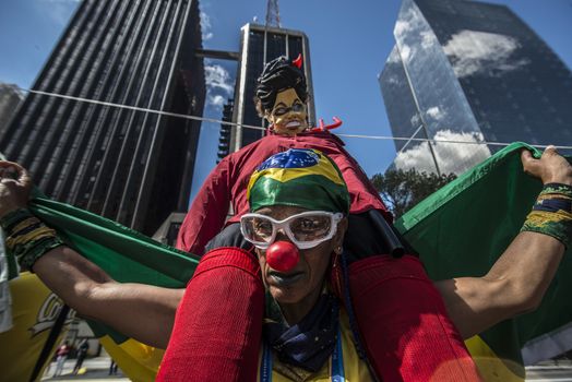 BRAZIL, Sao Paulo: A man holds a Brazilian flag with an effigie of President Dilma Rousseff on his shoulders during a demonstration for the impeachment of President Dilma Rousseff, against former president Lula and against corruption in Petrobras scandal case in Sao Paulo, Brazil on March 26, 2016. Brazilian lawmakers relaunched impeachment proceedings against President Dilma Rousseff Thursday and a judge blocked her bid to bring her powerful predecessor into her cabinet, intensifying the political crisis engulfing her. 