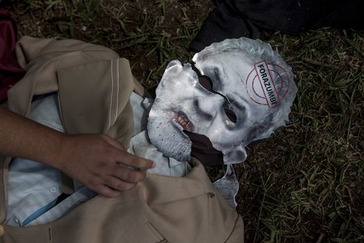 BRAZIL, Curitiba: A man wears a mask of a zombie of Brazilian former president (2003-2011) Luiz Inacio Lula da Silva known as Lulaas protesters beat effigies of President Dilma Rousseff and former President Lula in front of the Federal Court in Curitiba, Brazil on March 26, 2016. Traditionally on the Saturday before Easter, Catholics beat effigies of Judas the apostle. This year protesters in favor of impeachment of the President of Brazil, used the tradition as a political demonstration.