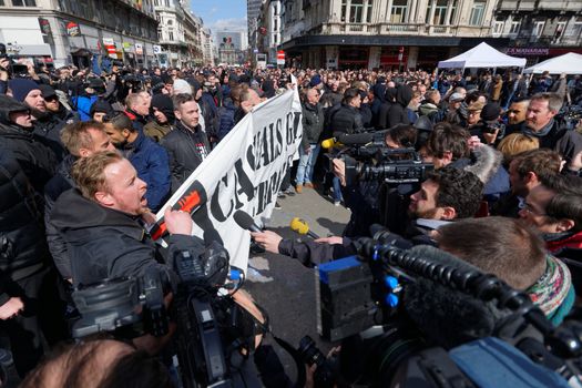 BELGIUM, Brussels : Far-right football hooligans chant slogans as they hold a banner of the FCK-Casuals hooligan movement, as they arrive in the square outside the stock exchange in Brussels on March 27, 2016 an area which has become an unofficial shrine to victims of the March 22, terror attacks claimed by the Islamic State (IS) group in which 31 people were killed and over 300 injured.Police fired water a cannon at far-right football hooligans who invaded a square in the Belgian capital that has become a memorial to the victims of the Brussels attacks, an AFP journalist said. Police took action after about 200 black-clad hooligans shouting nationalist and anti-immigrant slogans moved in on the Place de la Bourse where people were gathering in a show of solidarity with the victims.