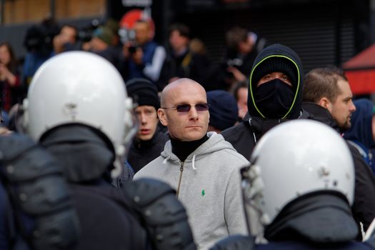 BELGIUM, Brussels : Far-right football hooligans face police outside the stock exchange in Brussels on March 27, 2016 an area which has become an unofficial shrine to victims of the March 22, terror attacks claimed by the Islamic State (IS) group in which 31 people were killed and over 300 injured.Police fired water a cannon at far-right football hooligans who invaded a square in the Belgian capital that has become a memorial to the victims of the Brussels attacks, an AFP journalist said. Police took action after about 200 black-clad hooligans shouting nationalist and anti-immigrant slogans moved in on the Place de la Bourse where people were gathering in a show of solidarity with the victims.