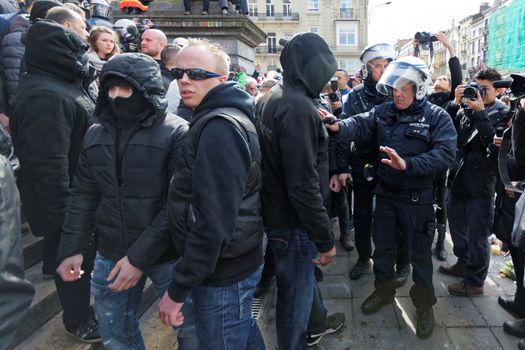 BELGIUM, Brussels : Far-right football hooligans face police outside the stock exchange in Brussels on March 27, 2016 an area which has become an unofficial shrine to victims of the March 22, terror attacks claimed by the Islamic State (IS) group in which 31 people were killed and over 300 injured.Police fired water a cannon at far-right football hooligans who invaded a square in the Belgian capital that has become a memorial to the victims of the Brussels attacks, an AFP journalist said. Police took action after about 200 black-clad hooligans shouting nationalist and anti-immigrant slogans moved in on the Place de la Bourse where people were gathering in a show of solidarity with the victims.