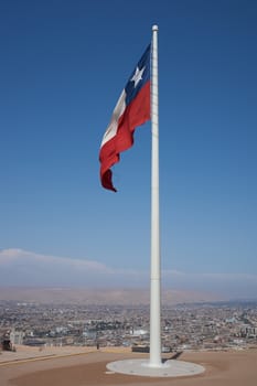 Chilean flag flying from the top of the Morro de Arica, a cliff that towers above the port city of Arica in Chile.