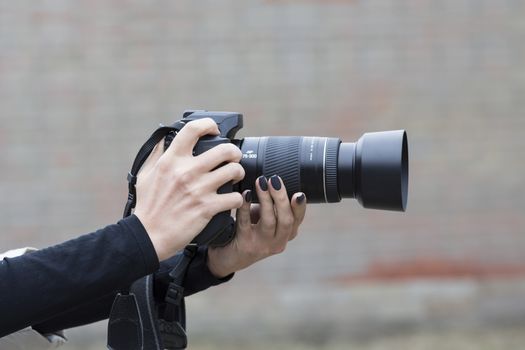 girl with beautiful manicure holds single-lens reflex camera