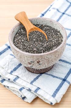 Nutritious chia seeds in ceramic bowl with wooden spoon for diet food ingredients.