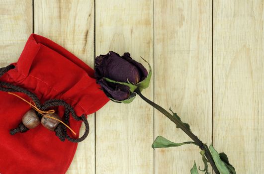 Dry roses with red small bag on wood pattern background
