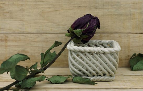 Dry roses and ceramic basket on wood pattern background