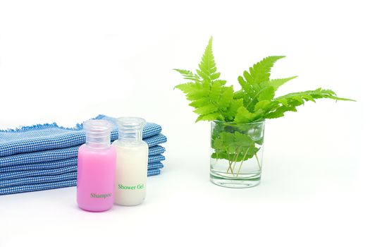 Shampoo and Shower gel on white background. Shampoo, Shower gel with blue cloth and green leaves in a glass of water.