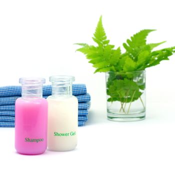 Shampoo and Shower gel on white background. Shampoo, Shower gel with blue cloth and green leaves in a glass of water.