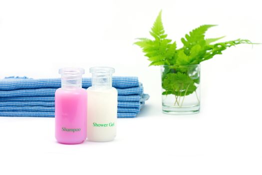 Shampoo and Shower gel on white background. Shampoo, Shower gel with blue cloth and green leaves in a glass of water.