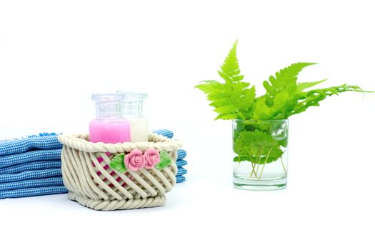 Shampoo and Shower gel put in ceramic basket on white background. Shampoo, Shower gel bottles with blue cloth and green leaves in a glass of water.