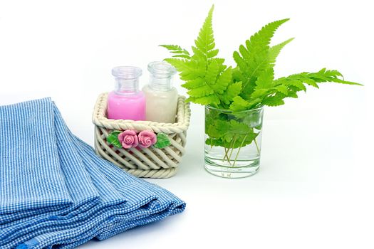 Shampoo and Shower gel put in ceramic basket on white background. Shampoo, Shower gel bottles with blue cloth and green leaves in a glass of water.