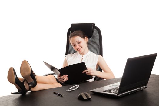 the business woman sits at office table with the laptop and reads the document