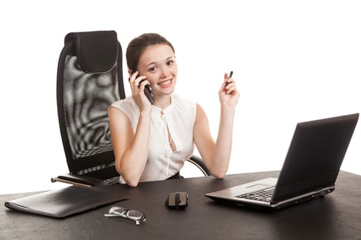 the business woman sits at office table with the laptop and speaks by phone
