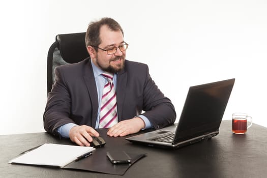 the businessman sits at office table with the laptop