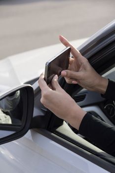 a girl takes pictures on a cell phone from the car window
