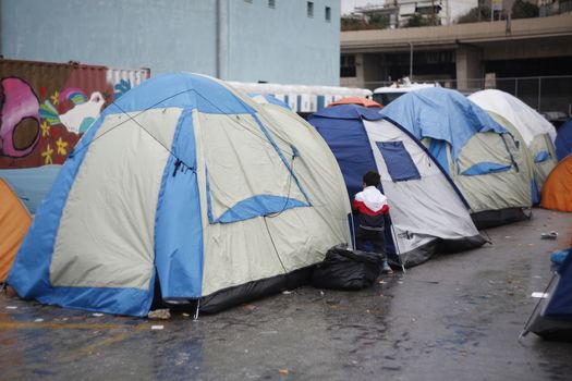 GREECE, Athens: Refugees continue to camp out under the rain, as thousands are still stranded at the Port of Piraeus in Athens, Greece on March 27, 2016. A deal between the European Union and Turkey has aimed to curb the influx of refugees to Greece, saying reception centers have become detention facilities. 