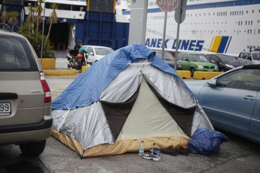 GREECE, Athens: Refugees continue to camp out under the rain, as thousands are still stranded at the Port of Piraeus in Athens, Greece on March 27, 2016. A deal between the European Union and Turkey has aimed to curb the influx of refugees to Greece, saying reception centers have become detention facilities. 