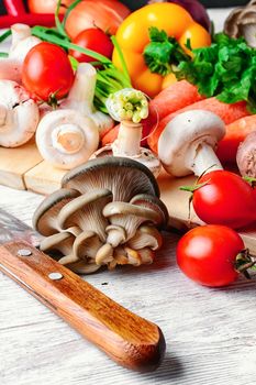 Fresh mushrooms,tomatoes,peppers and onions on a light wooden background