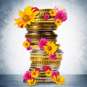 Stack of gold coins with flowers on grey wall background