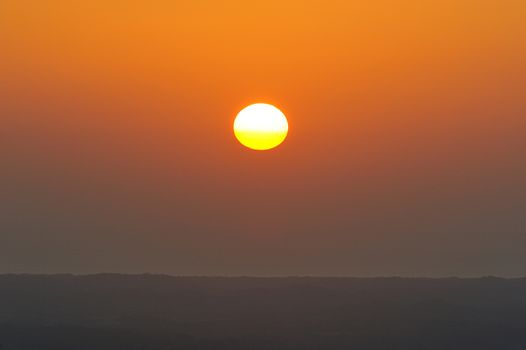 Red sun next to horizont line in orange sky