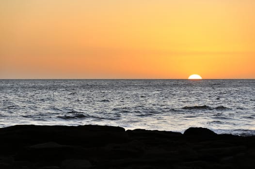 Sun half in horizon of still ocean