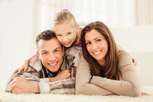 Portrait of a beautiful happy family at home. They are lying down and looking at camera.