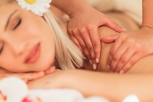 Close-up of young woman enjoying during a shoulder massage at a spa.