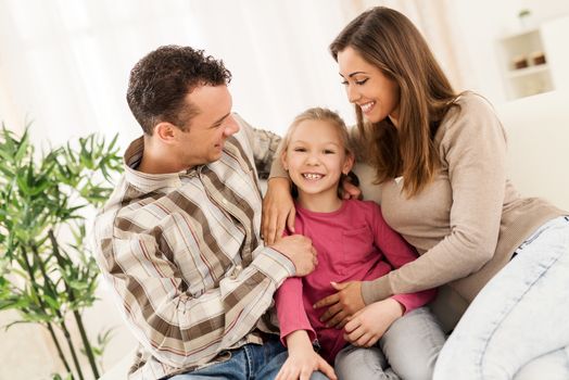 Beautiful young smiling family relaxing on sofa at living room.