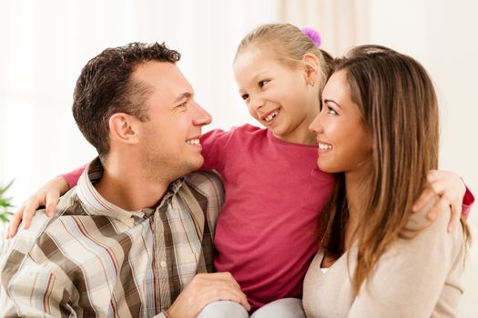 Beautiful young smiling family relaxing on sofa at living room.