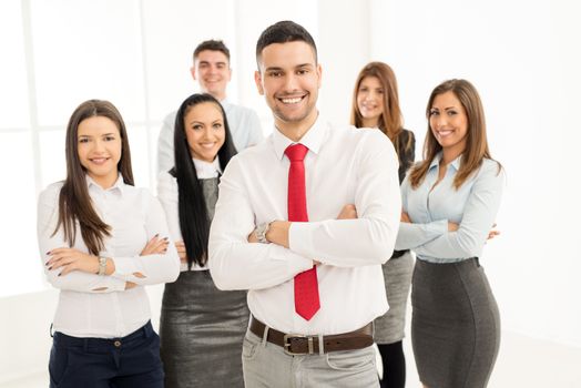 Successful arabian businessman with crossed arms standing proudly in front his young business team and looking at the camera.