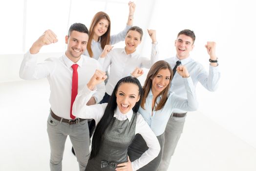 Group of young successful business people standing proudly with fist up and looking at camera.