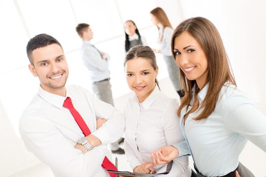 Three smiling young colleagues standing proudly in front his young business team and looking at the camera.