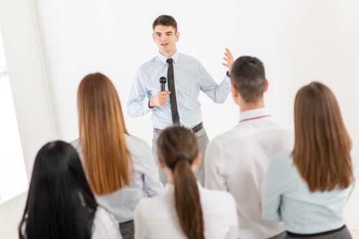 Young businessman explaining to her colleagues plan of work. The team is listening.