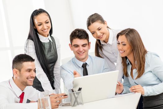 Successful young smiling colleagues working at laptop in the office.