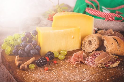 Fresh grapes, cheese bacon berries and salami on wooden table