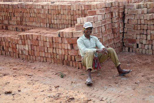 Brick field workers rest after hard work, wearing just baked brick from the kiln in truck in Sarberia, West Bengal, India.
