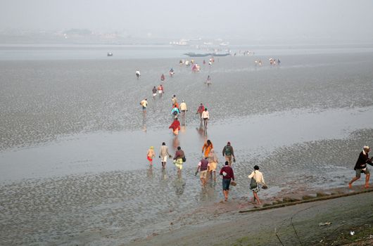 During low tide the water in the river Malta falls so low that people walk to the other shore in Canning Town, India