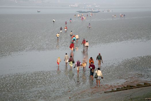 During low tide the water in the river Malta falls so low that people walk to the other shore in Canning Town, India