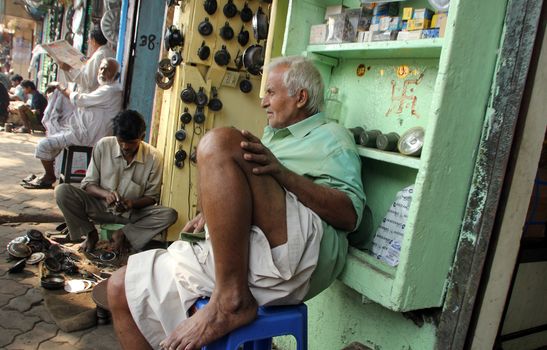 Indian man outside a shop selling car parts on Malik bazar in Kolkata, India