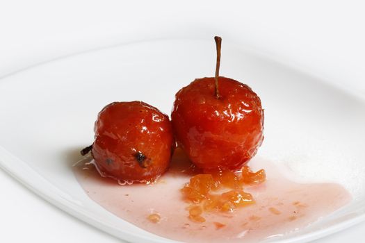 Red apples in rose syrup with small pieces of zucchini over isolated white background