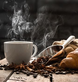 Hot coffee and croissant on old wooden table