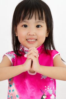 Chinese Little Girl wearing Cheongsam with greeting gesture in plain white background.