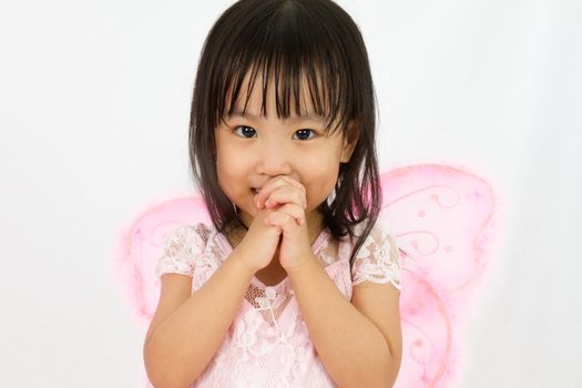 Chinese little girl wearing butterfly custome with praying gesture in plain white background
