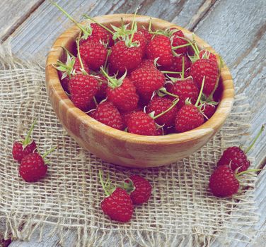 Wooden Bowl Full of Perfect Ripe Raspberries with Stems closeup on Rustic Wooden background