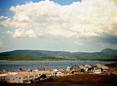 Small Menorca Urbanization Fornells between Hills and near Yacht Marina under Cloudy Skies Outdoors. Balearic Islands