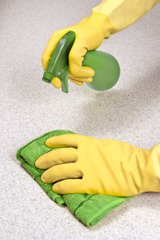 Vertical shot of cleaning the kitchen counter with rubber gloves and cleaning cloth.