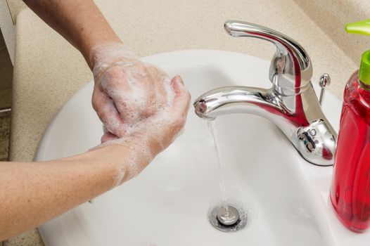 Woman washing her hands with liquid soap.